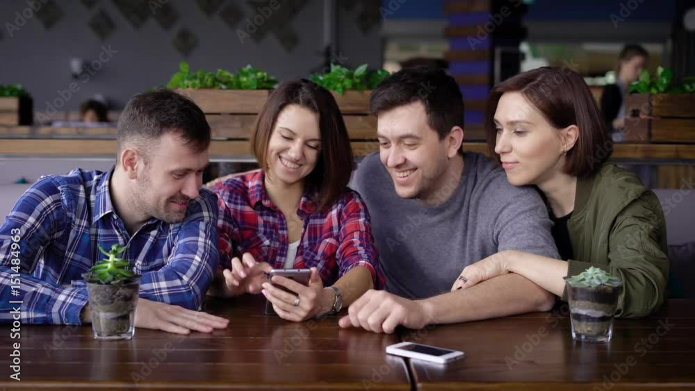 Friends watching smart phone while sitting in restaurant Friends watching smart phone while sitting in restaurant