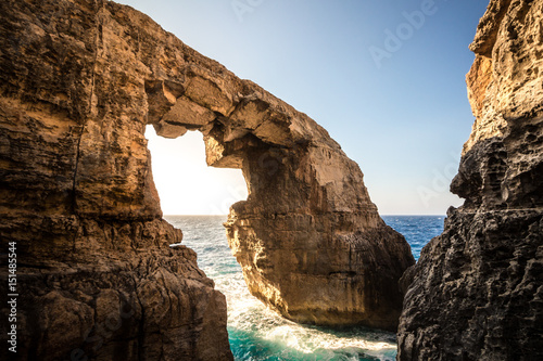 The stone sea arch at wied il-Mielah, Gozo, Malta. Sunny weather, bright sunlight golden hour. © raphoto