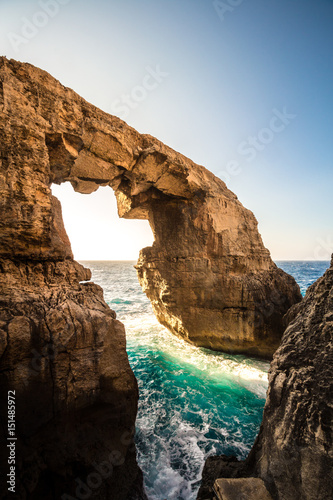 The stone sea arch at wied il-Mielah, Gozo, Malta. Sunny weather, bright sunlight golden hour.