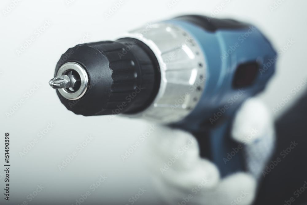 Electric screwdriver in hand at white desk background Electric screwdriver in hand at white desk background