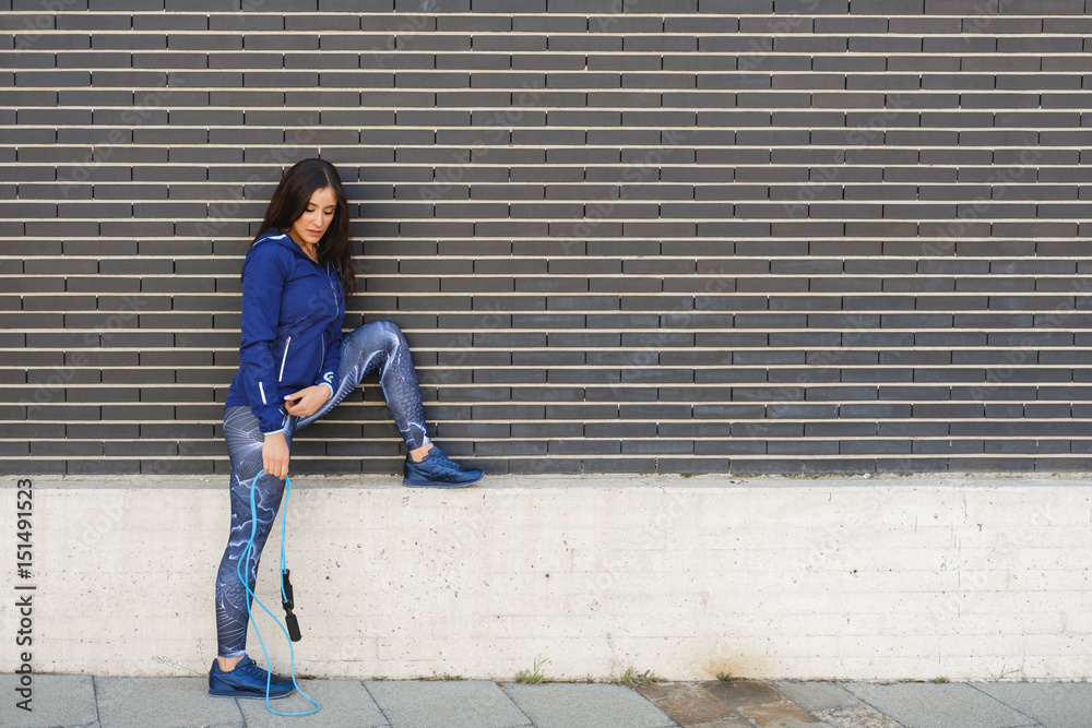 Fitness woman resting after jumping rope. Urban outdoor healthy workout. Fitness woman resting after jumping rope. Urban outdoor healthy workout.