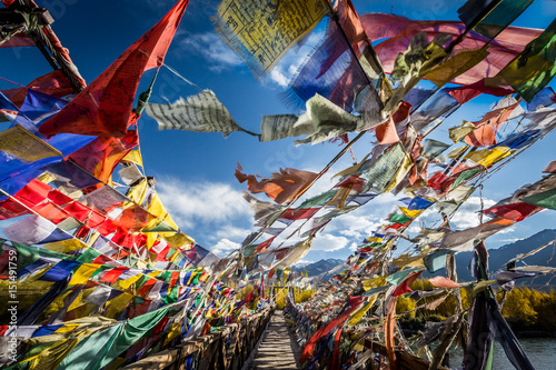 Fotografia Colourful Buddhist prayer flags on a bridge above Indus river in the Himalayan m