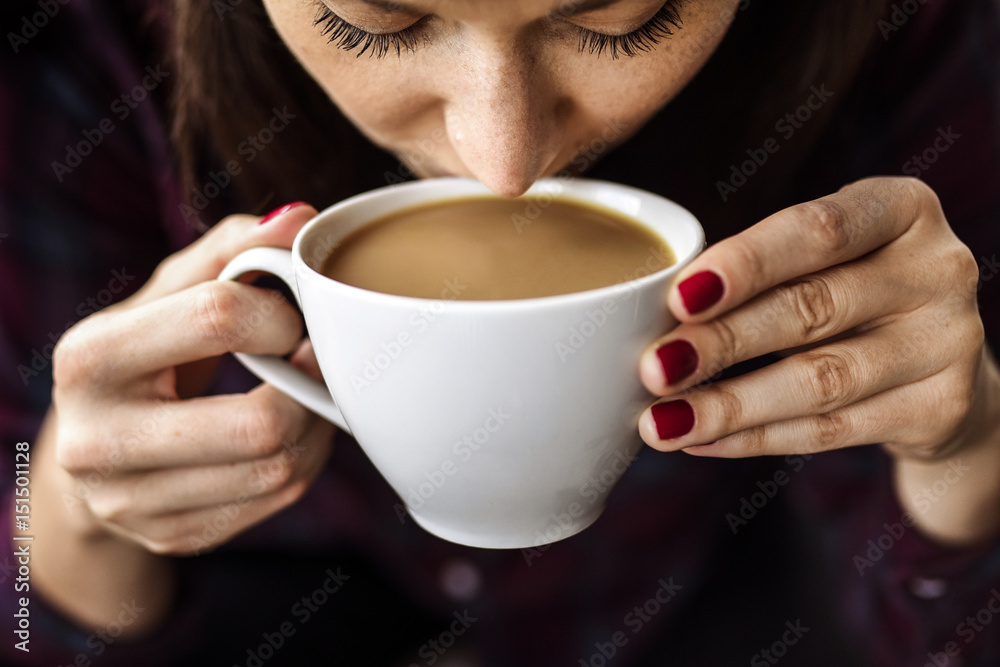 White young woman holding a cup of coffee in her hands and drinking it while coffee break. White young woman holding a cup of coffee in her hands and drinking it while coffee break.