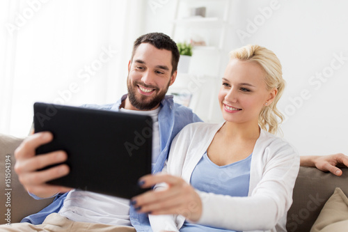 smiling happy couple with tablet pc at home