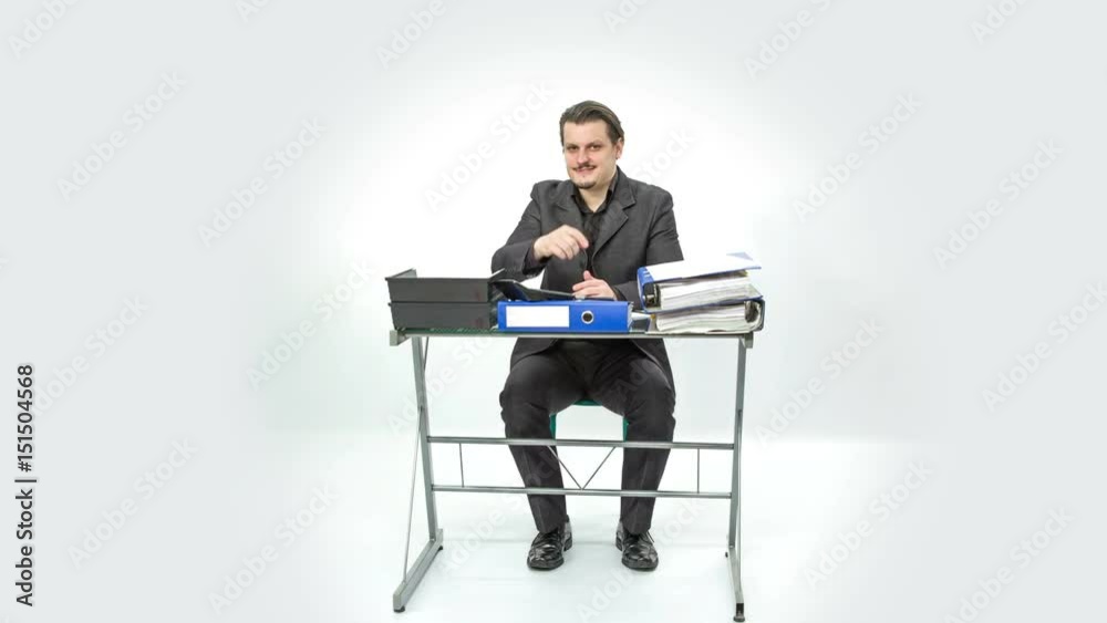 A man is sitting at his desk and he is pointing at someone. He looks happy.