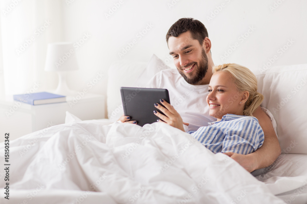 smiling happy couple with tablet pc in bed at home smiling happy couple with tablet pc in bed at home