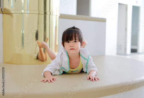 Portrait of asian child girl in swimming suit looking straight and lying on sofa.