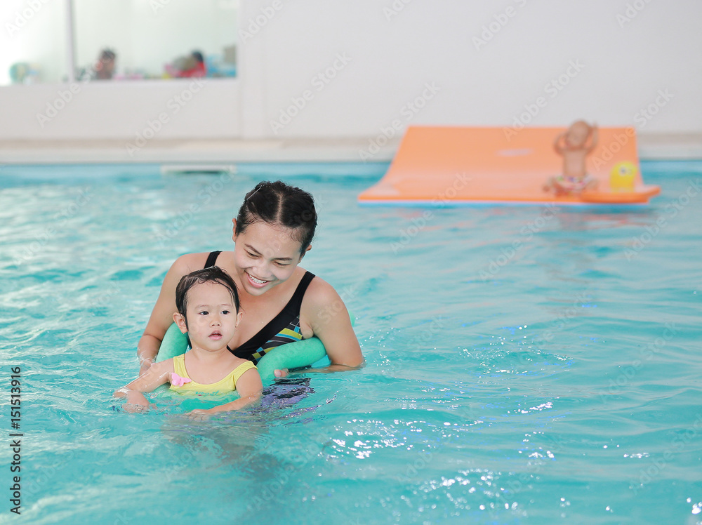 Close up mother teaching kid in swimming pool.