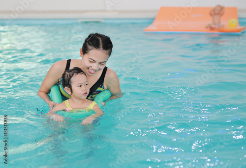 Close up mother teaching kid in swimming pool. © zilvergolf