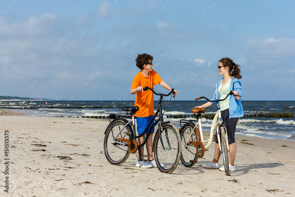 Teenage girl and boy biking on beach