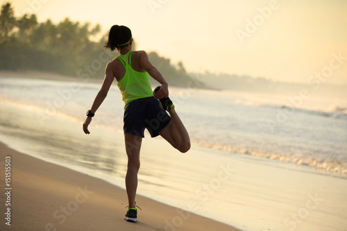 healthy lifestyle young woman runner stretching legs before running on sunrise seaside
