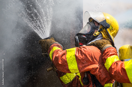 firefighter water spray by high pressure fire hose in smoke and droplets