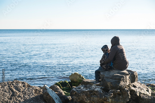 Back view of a mother and his son walking on the sea shore
