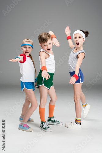 Fototapeta Naklejka Na Ścianę i Meble -  Adorable sporty kids in sportswear standing together and posing isolated on grey, children sport concept