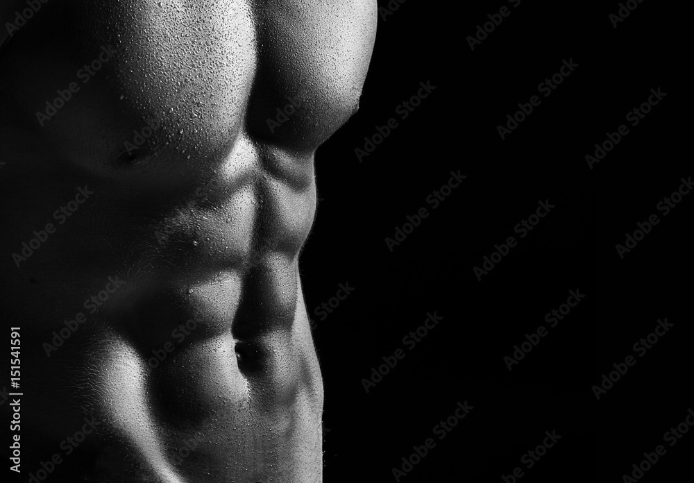 The torso of attractive male body builder on black background. The torso of attractive male body builder on black background.