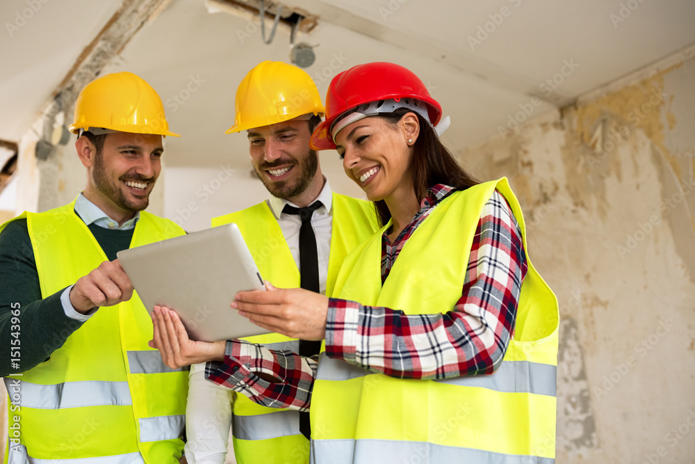 Group of young arhitects with l tablet on construction site Group of young arhitects with l tablet on construction site