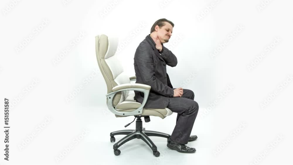 A young man is having a stiff neck and a pain in his lower back. He is trying to relax a bit. A young man is having a stiff neck and a pain in his lower back. He is trying to relax a bit.