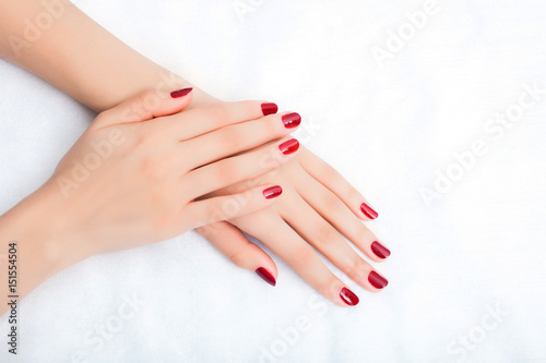 Female hands with manicure and red lacquer on a white table photo