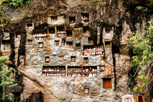 Old torajan burial site in Lemo, Tana Toraja. The cemetery with coffins placed in caves carved into the rock and balconies with dressed wooden statues tau tau. Rantapao, Sulawesi, Indonesia photo