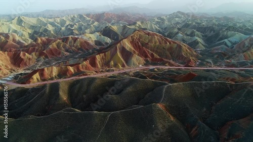Aerial view on grass-covered sandstone hills in front of a colorful Rainbow Mountain in a Geopark. Part 3 of a 3 part series which can be merged to a continuous movie. 