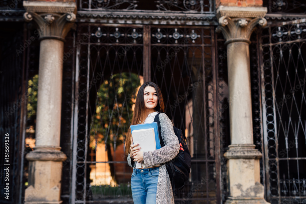 Smiling pretty young woman student with backpack walking outdoors near campus Smiling pretty young woman student with backpack walking outdoors near campus