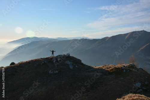 Donna con le braccia aperte in cima ad una montagna 