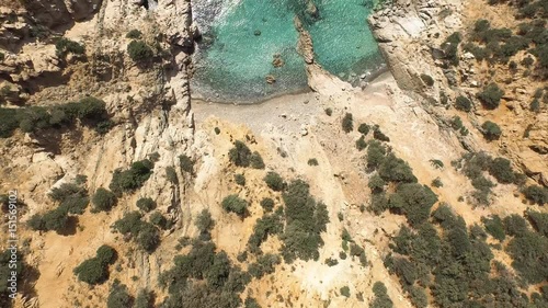Drone fly over sardinia coastline and colorful turquoise mediterranean sea surraunded by high cliff and ancient ruins of a watchtower