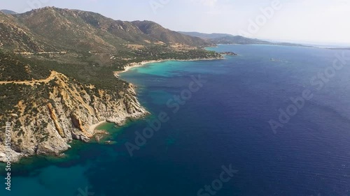 Drone fly over sardinia coastline and colorful turquoise mediterranean sea surraunded by high cliff and ancient ruins of a watchtower