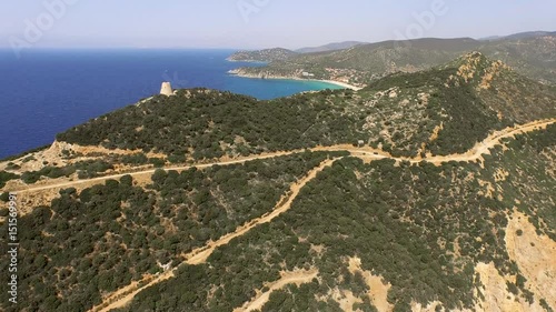 Drone fly over sardinia coastline and colorful turquoise mediterranean sea surraunded by high cliff and ancient ruins of a watchtower
