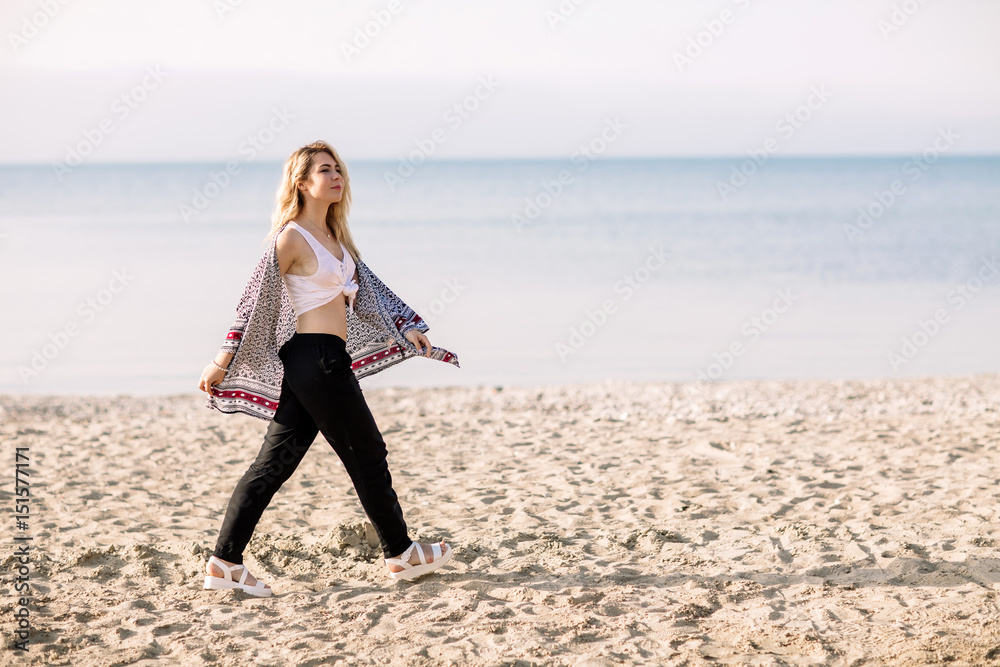 Blonde girl on the beach of the sandy beach by the sea