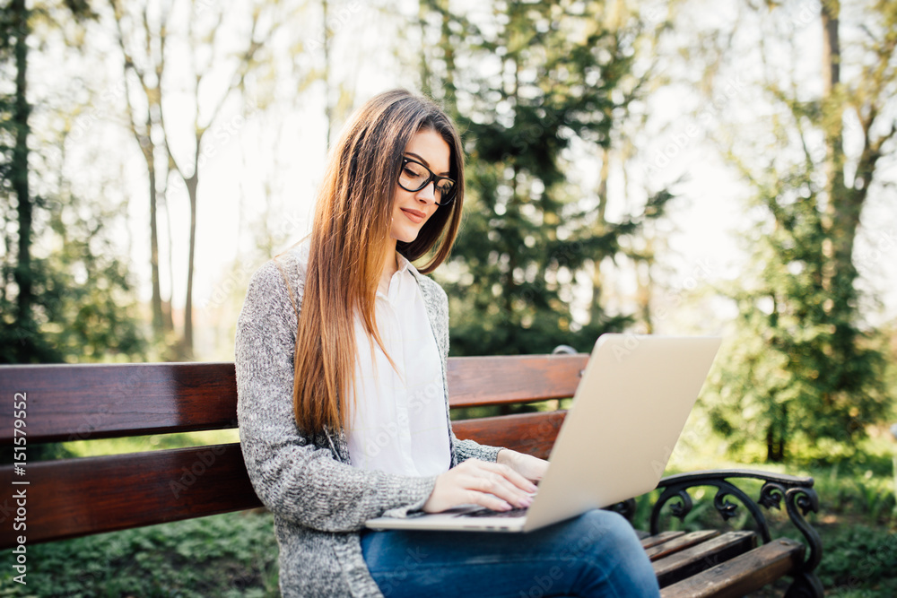 Young girl on a bench with a laptop in park Young girl on a bench with a laptop in park
