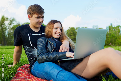 A young couple with  laptop resting in the park. © Studio Romantic