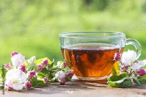 tea time/cup of tea and apple flowers on wooden table outdoors