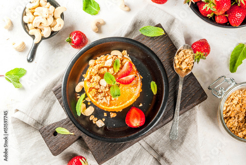 Ideas for healthy vegan breakfast. Paleo diet. Grilled oranges grapefruits with brown cane sugar  granola  honey  strawberry slices  cashew nuts and mint. On a white stone table copy space 