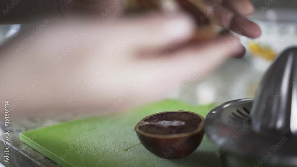 Close up of woman s hands cutting a citrus fruit with a knife and squeezing its juice with a manual juicer. Locked down real time close up shot Close up of woman s hands cutting a citrus fruit with a knife and squeezing its juice with a manual juicer. Locked down real time close up shot