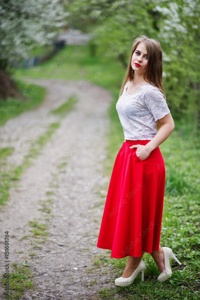 Portrait of beautiful girl with red lips at spring blossom garden, wear on red dress and white blouse. Portrait of beautiful girl with red lips at spring blossom garden, wear on red dress and white blouse.