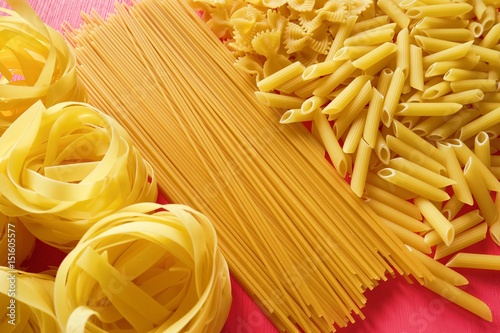 The yellow pasta tubes on a bright pink wooden background