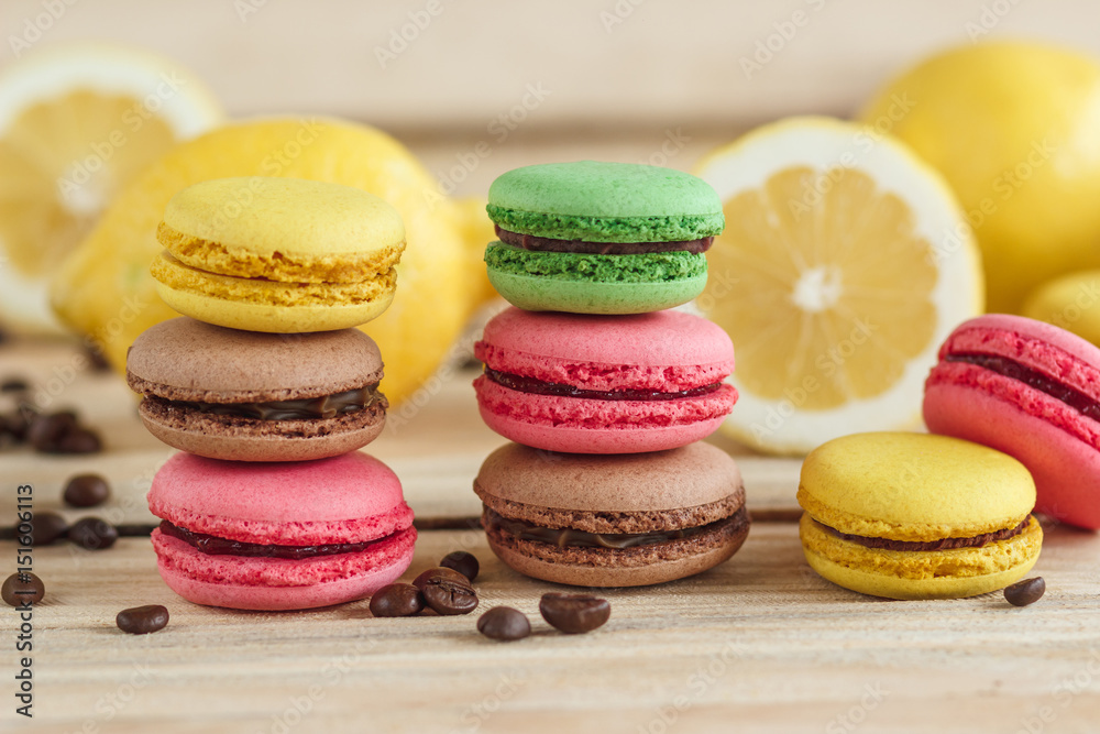 Green, pink, yellow and brown french macarons with lemon and coffee beans