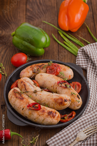 Grilled sausages in frying pan. Wooden background. Top view. Close-up
