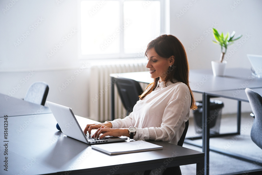Concentrated at work. Young beautiful woman using her laptop while sitting in chair at her working place. Concentrated at work. Young beautiful woman using her laptop while sitting in chair at her working place.