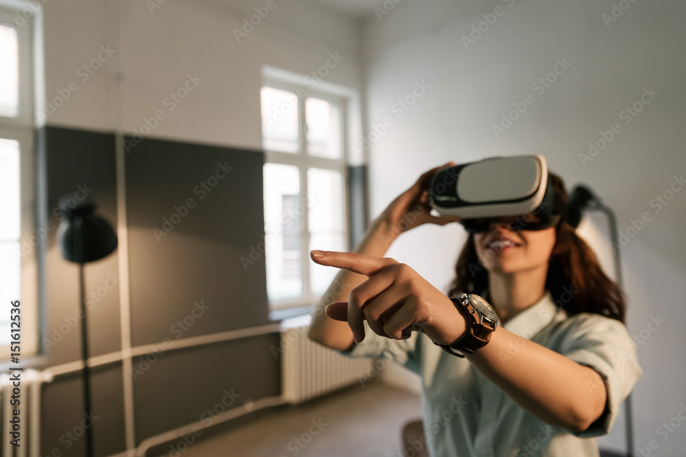 Smiling happy woman getting experience using VR-headset glasses