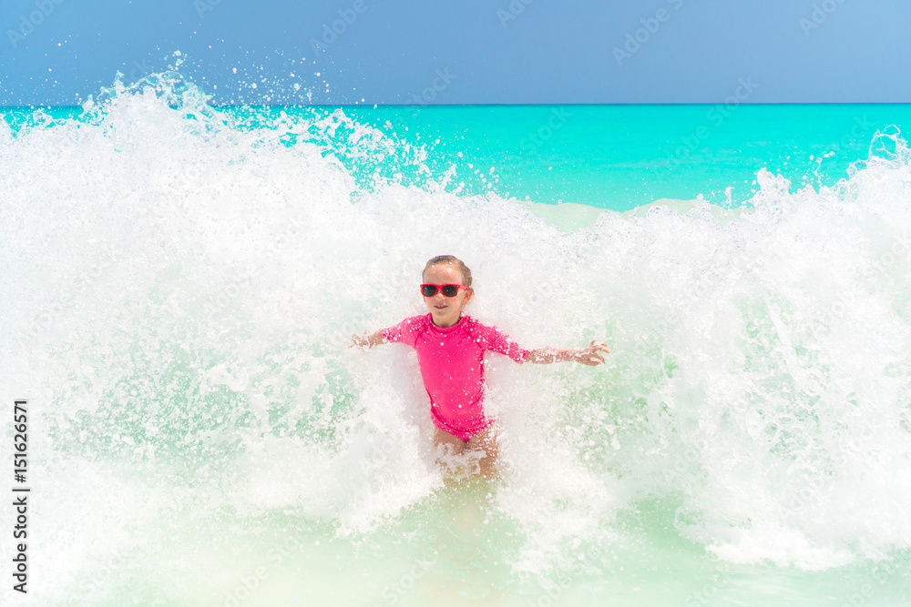 Adorable little girl at beach having a lot of fun in water