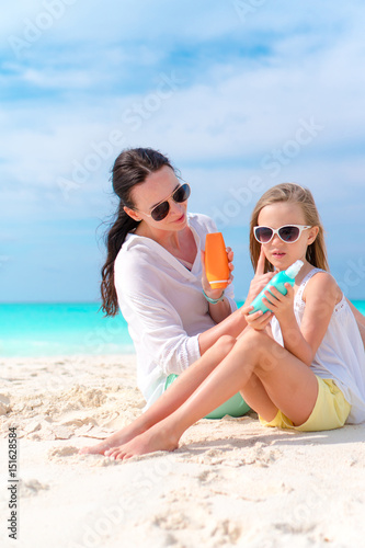 Mom applying sun cream to kid nose on the beach. The concept of protection from ultraviolet radiation