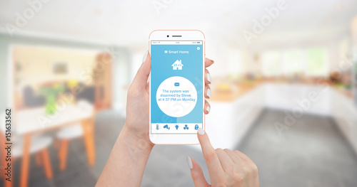 Female hand holding smartphone with home control application and reading a notification that smart house system was disabled by her husband. Smart home concept