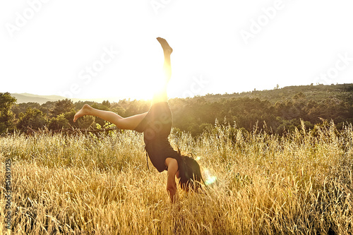Chica levantando piernas en puesta de sol photo
