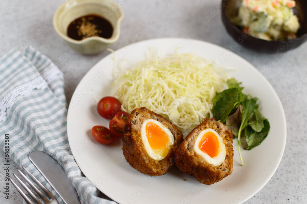 a plate of soft boiled scotch egg accompanied with fresh vegetable and potato salad