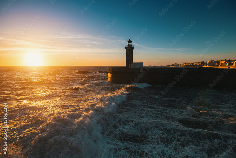 Beautiful sunset on the ocean lighthouse at coast of Portugal.