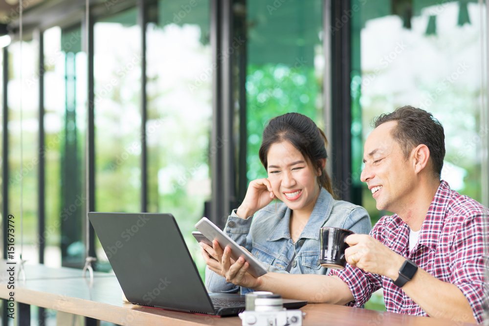 Asian young woman and old man are enjoy with tablet and laptop at coffee shop. Casual meeting outside office concept. A Girl is teaching technology for her father. Funny and hapyy moment. Asian young woman and old man are enjoy with tablet and laptop at coffee shop. Casual meeting outside office concept. A Girl is teaching technology for her father. Funny and hapyy moment.