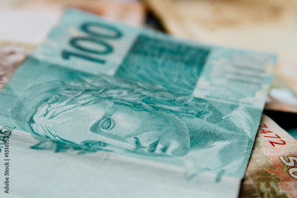 Fototapeta premium Macro closeup of a 100 Brazilian reais banknote on 50 reais notes on background