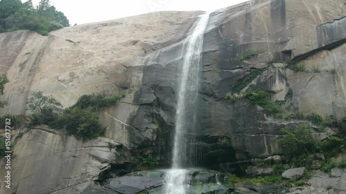 waterfall on cliffs in mountains,flowing into pond lake. photo